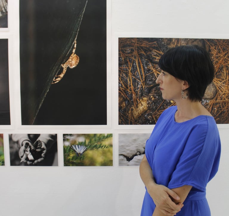 Asimina Georgakopoulou facing photographs during an exhibition by the Eyes of Light Organization