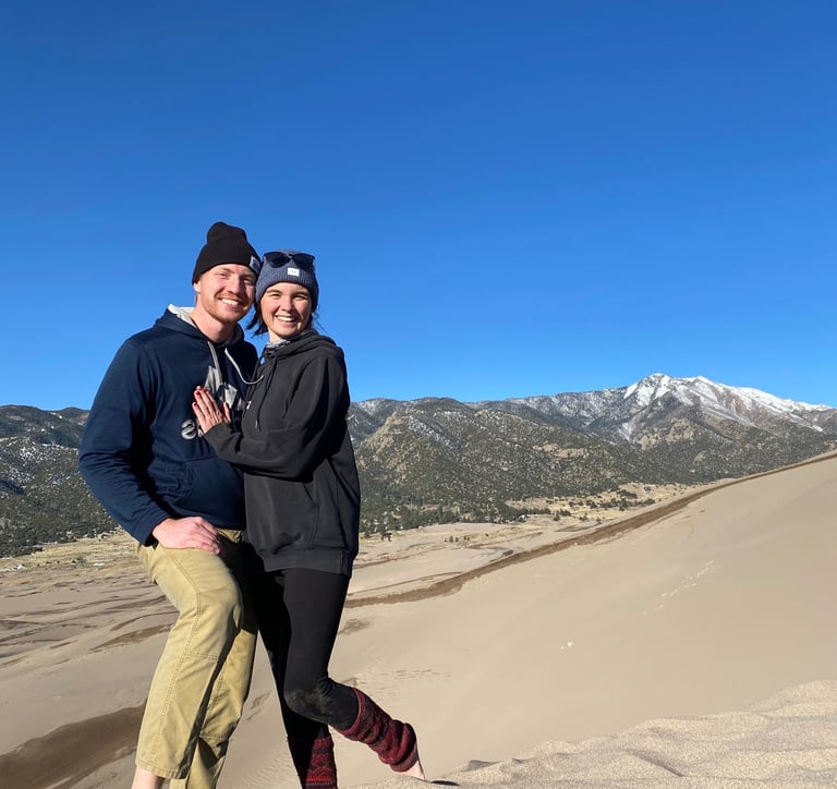 Alex and Nick smiling together on the sand dunes at Great Sand Dunes National Park