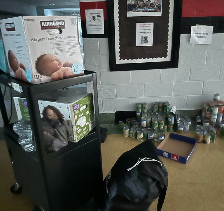 A dark middle school hall food pantry with cans of food and baby supplies during Hurricane Helene