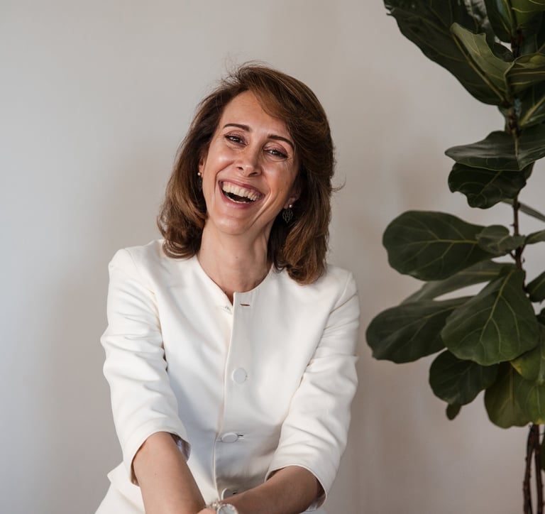 a female life coach in a white suit, smiling