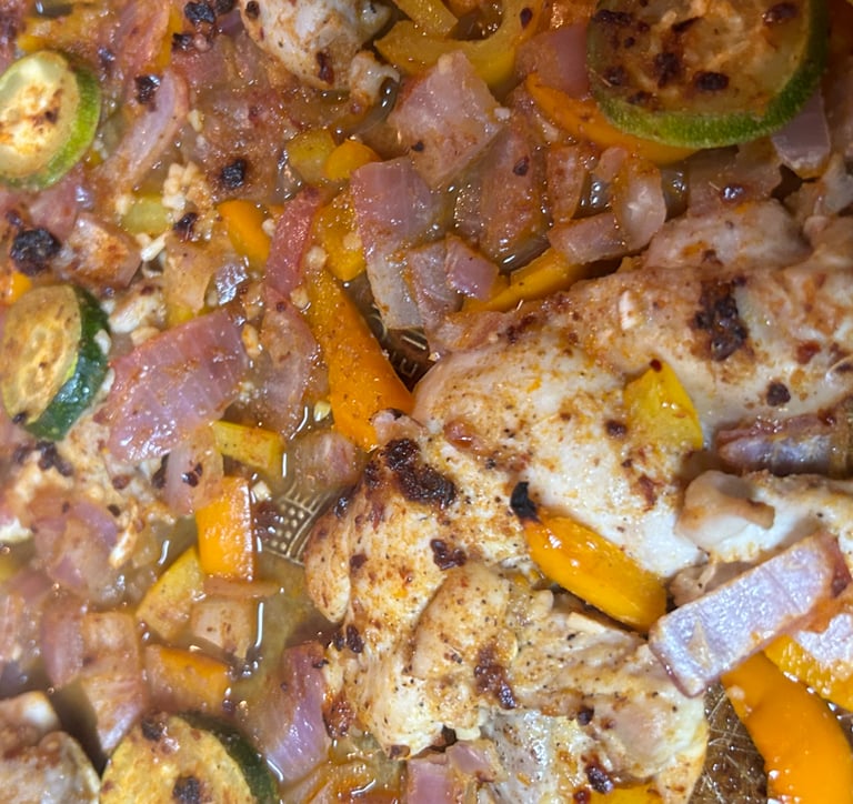 Baked chicken and vegetables on a baking pan just out of the oven.