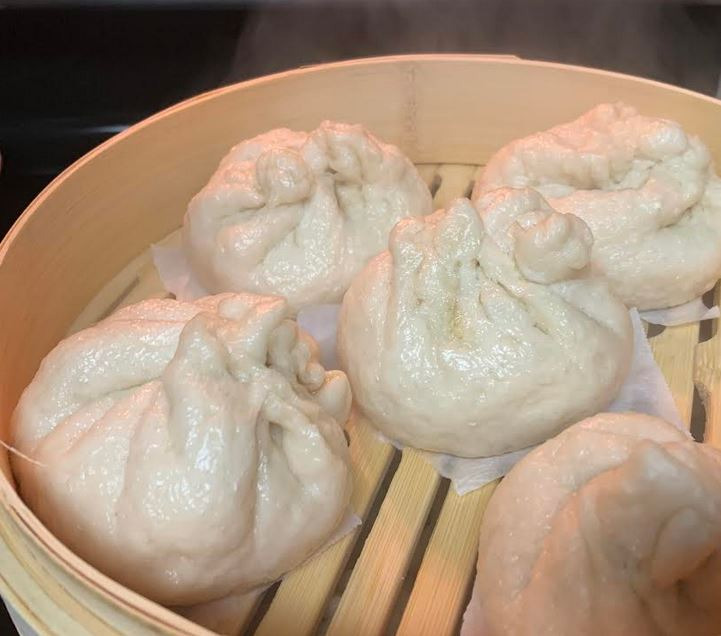 Steamed dumplings in bamboo steamer with steam rising. For FlavorfulBites