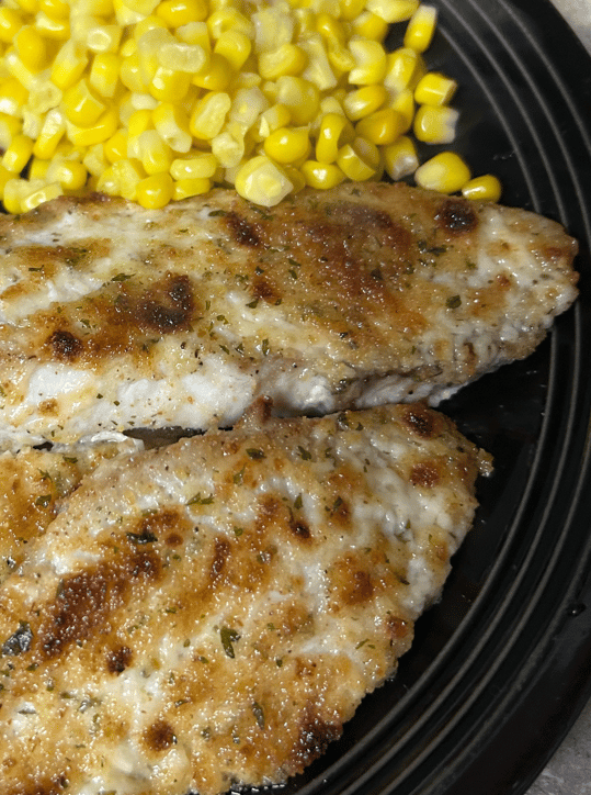 Broiled talapia on a plate with corn.