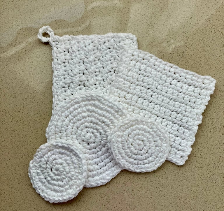 5 white crocheted face scrubbies lying on each other in round and square shapes