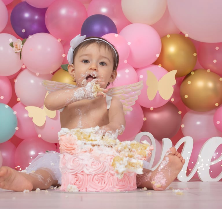 a baby girl sitting in front of a cake