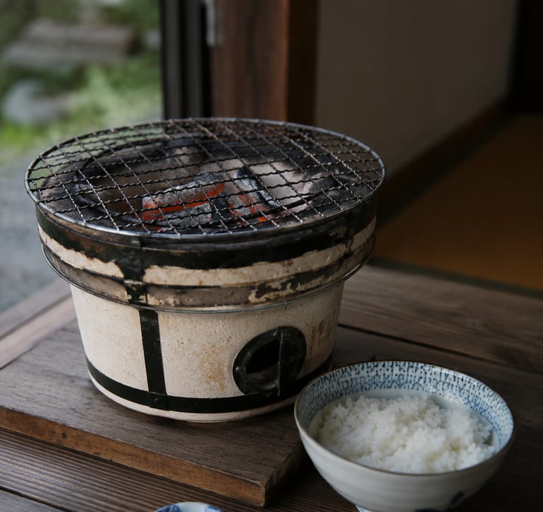 Traditional Japanese shichirin charcoal grill with glowing coals and a bowl of steamed white rice.