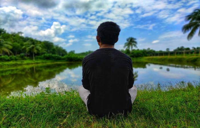 a man sitting on the grass in front of a lake