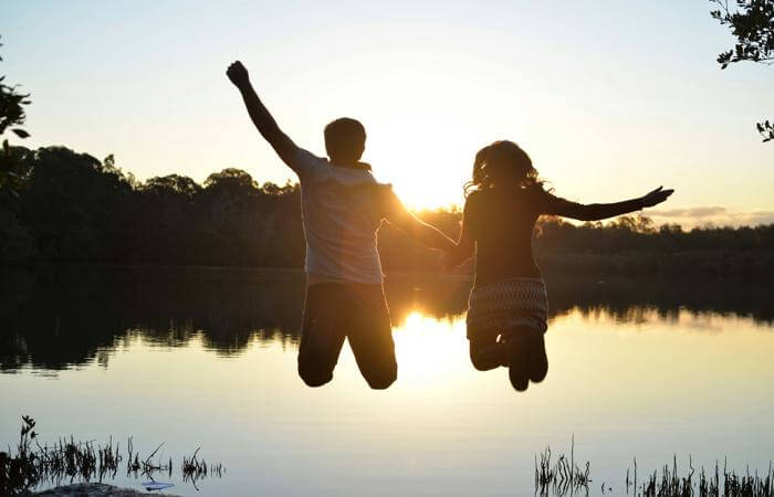 two people jumping in the air with their hands up