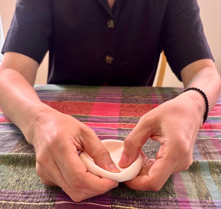 In an expressive arts therapy session, a person molds a clay ball into a bowl using their hands