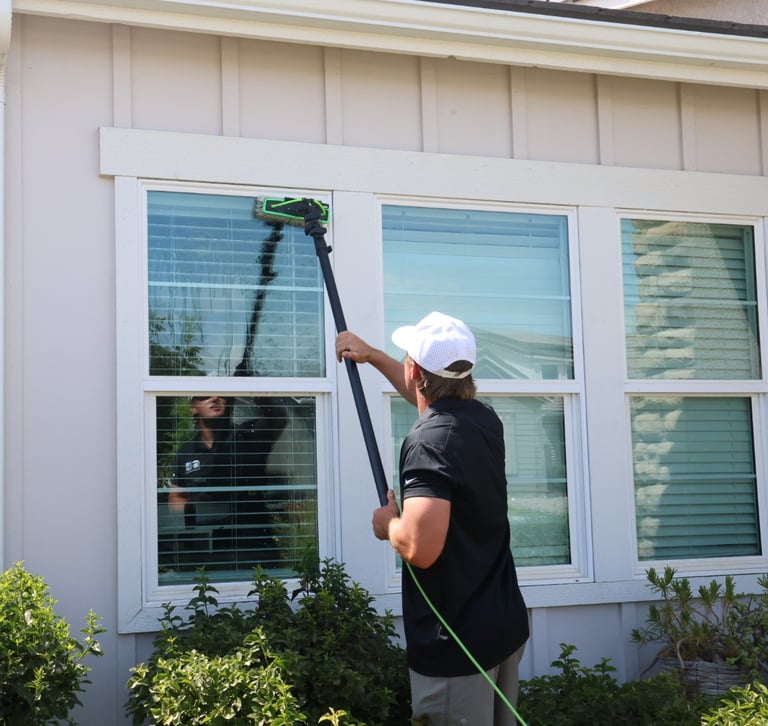 kyler using the waterfed pole to clean a windows frames, glass, and sills
