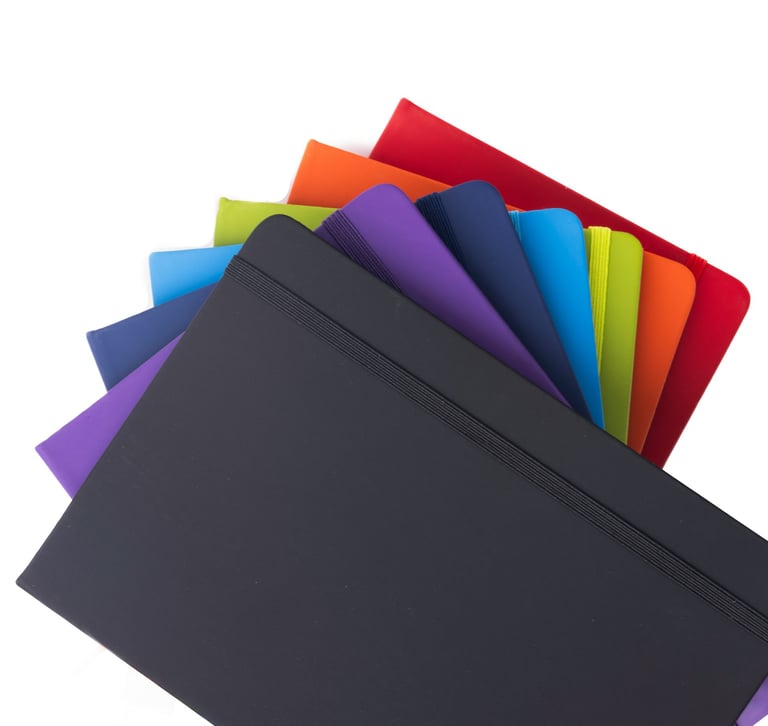 A fanned-out stack of colorful hardcover folders with elastic closures on a white background.
