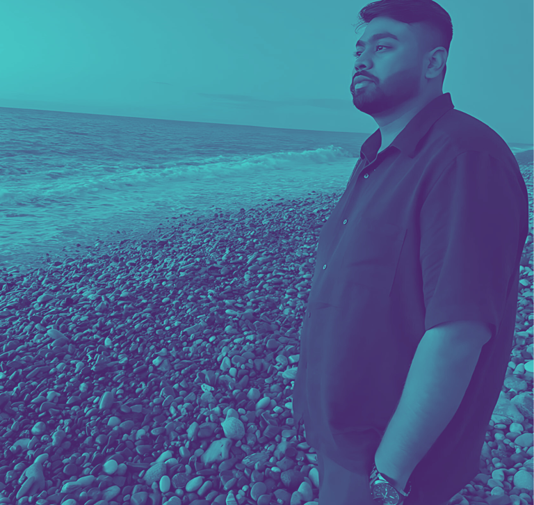 Sarang Vhankade standing on a beach around rocks