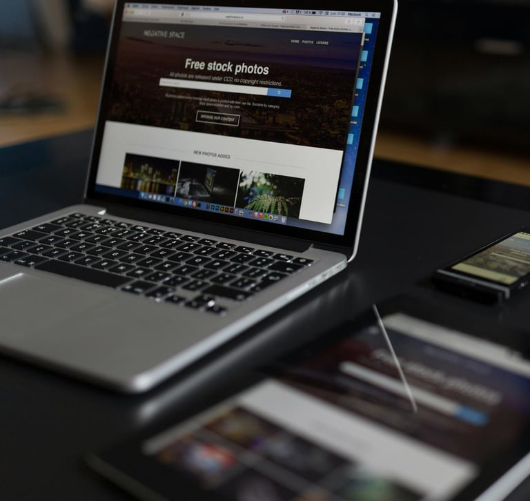 Um laptop, um tablet e um smartphone sobre uma mesa escura exibem uma site.