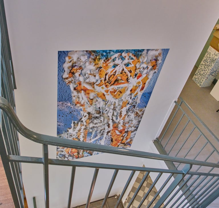 A colorful portrait painting on a wall viewed from a modern staircase with metal railings.