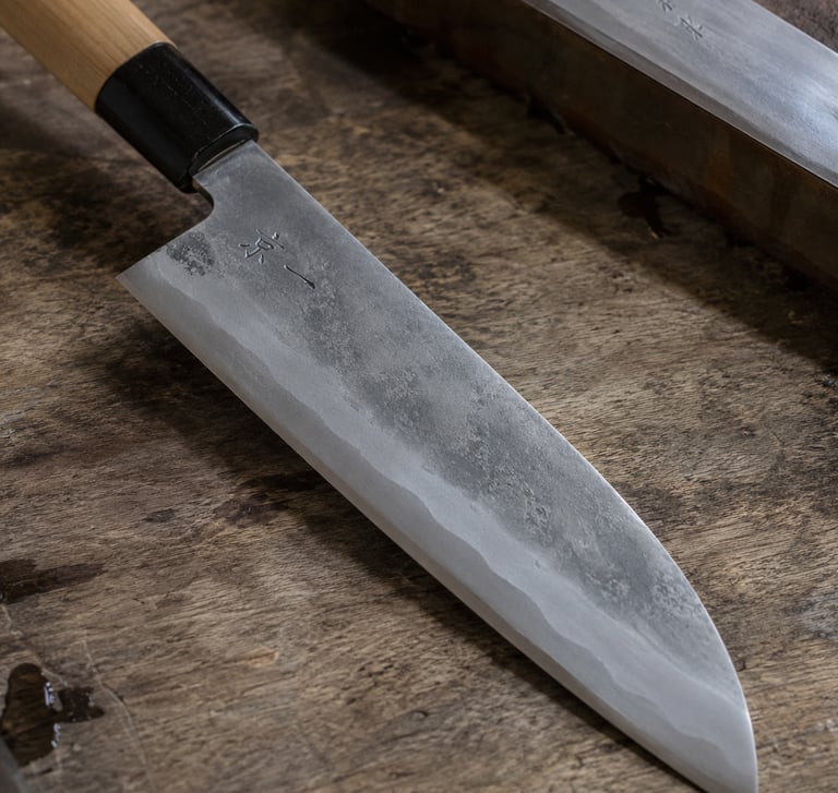 A handcrafted Japanese chef knife with a high-carbon steel blade resting on a rustic wooden surface.