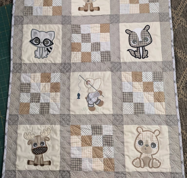 Patchwork quilt with plaid squares and embroidered woodland animals in a playful 4x5 grid.
