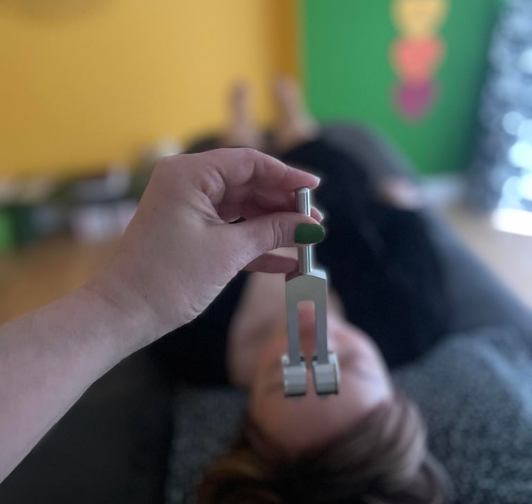 A hand holding a tuning fork during a sound therapy session