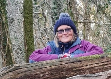 a woman in a purple jacket and a blue jacket forest bathing and shinrin yoku