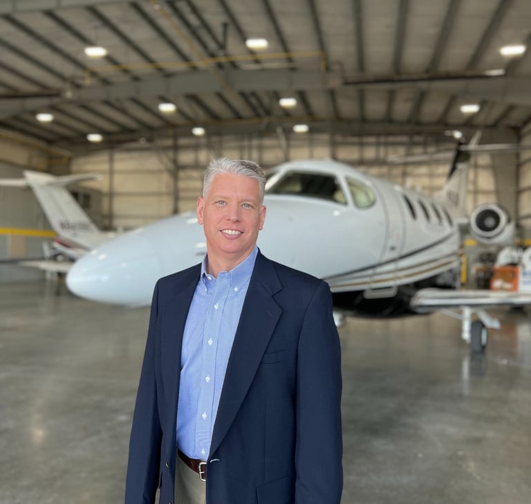a man in a suit and tie standing in a hangar