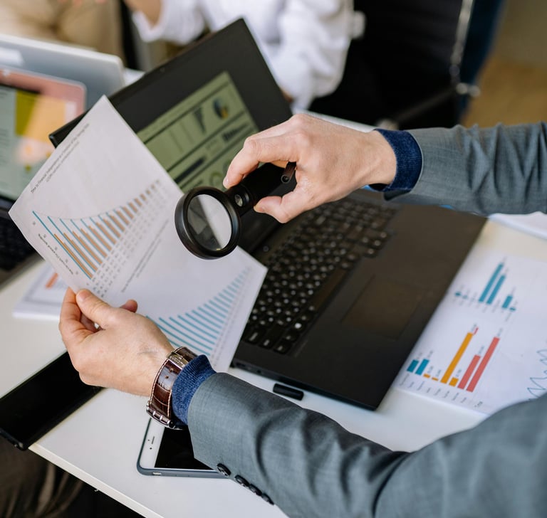 Professional examining financial growth charts with a magnifying glass during a business data analysis session.