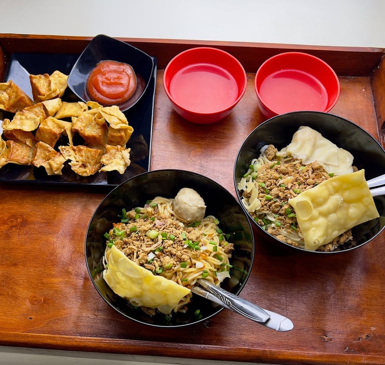 Tray berisi dua mangkuk mie ayam dengan topping lengkap, dua mangkuk saus, dan pangsit goreng