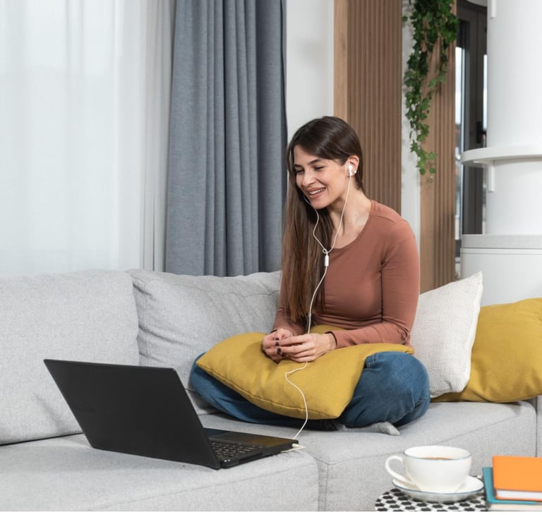 a woman sitting on a couch with a laptop and headphones