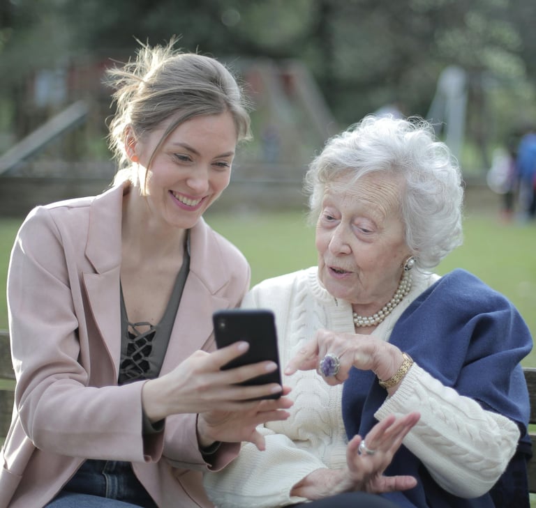 Young woman and elderly woman using smartphone together on a bench