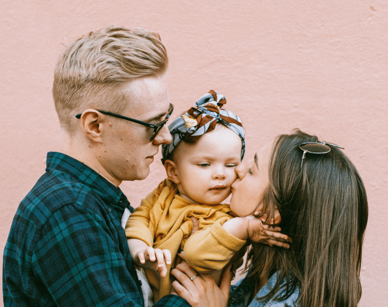 Parents sharing a tender moment kissing their young daughter
