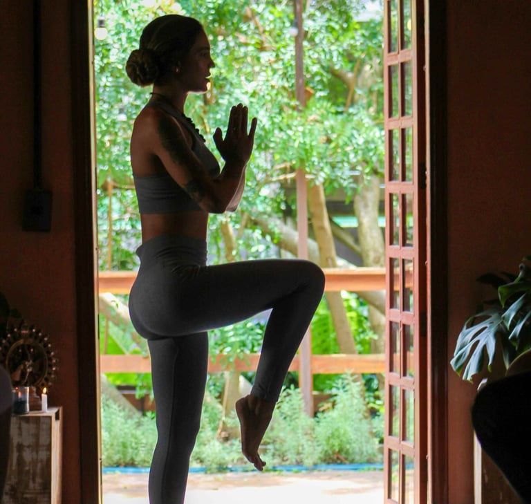 Frau übt Yoga vor einer offenen Tür mit Blick in den Garten