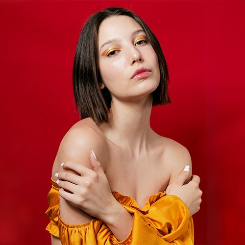 a woman with a bright orange top and a gold ring