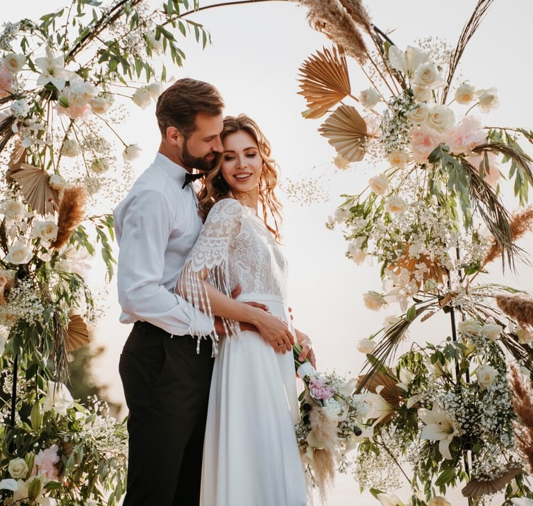 a bride and groom standing in front of a floral arch