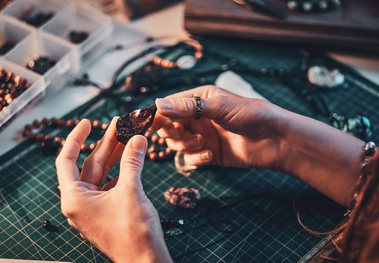 mujer creando collares a mano con piedras