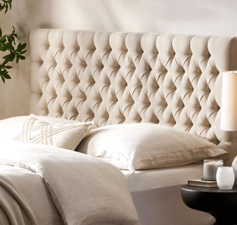 Cream tufted headboard with linen bedding and decorative pillows in a modern bedroom.