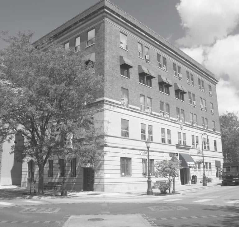 A black and white photo of a historic multi-story brick building on a city street corner.
