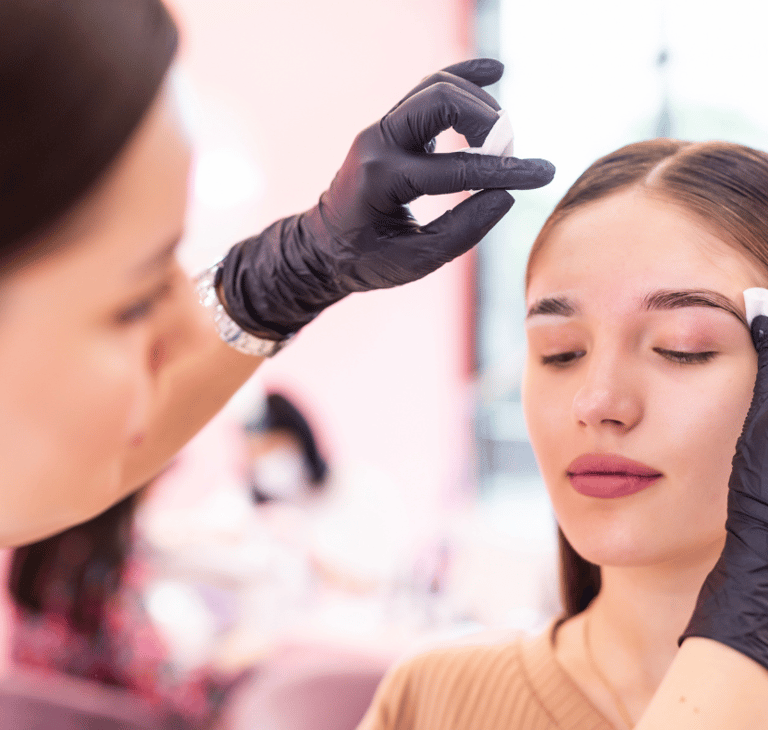 a woman getting her eyebrows done by a professional brow artist