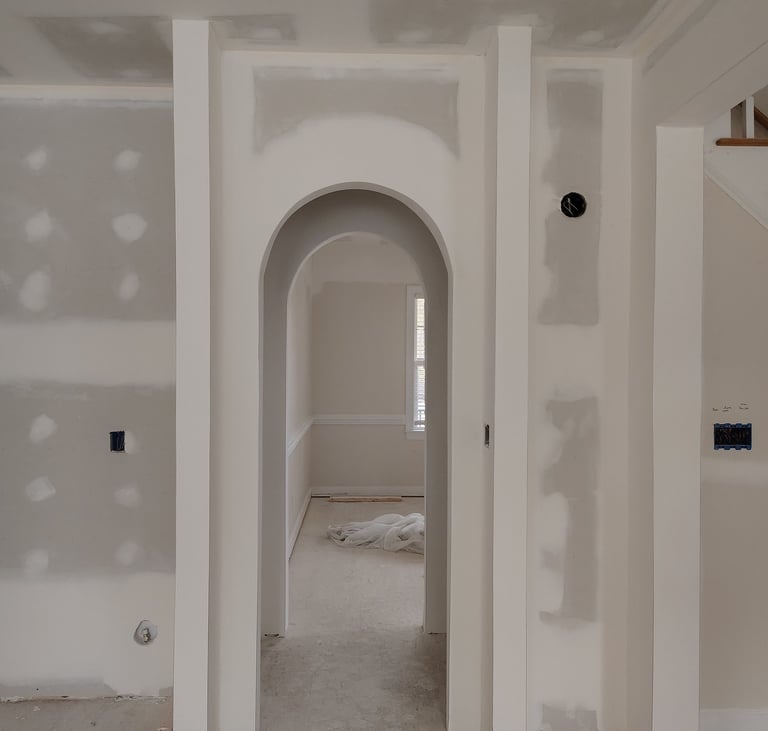 An interior home renovation featuring newly installed arched doorways and smooth finished drywall.