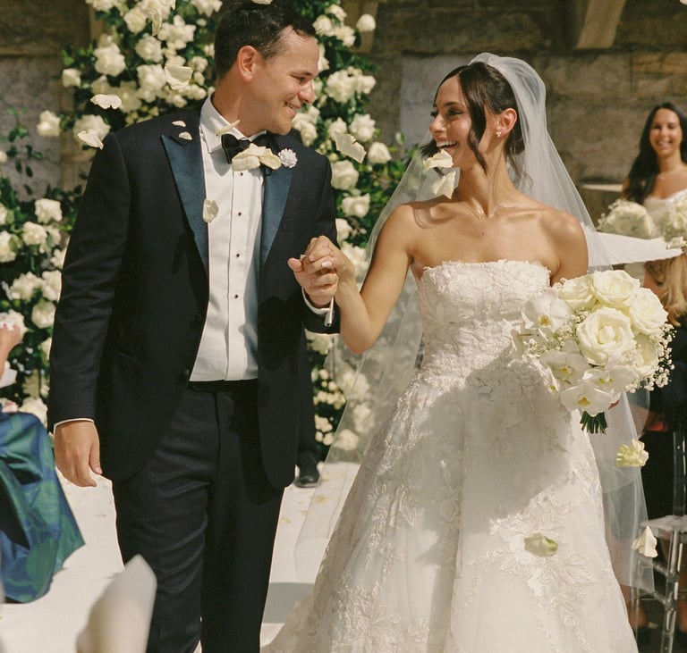 Happy just married couple walking down the aisle full of white flowers