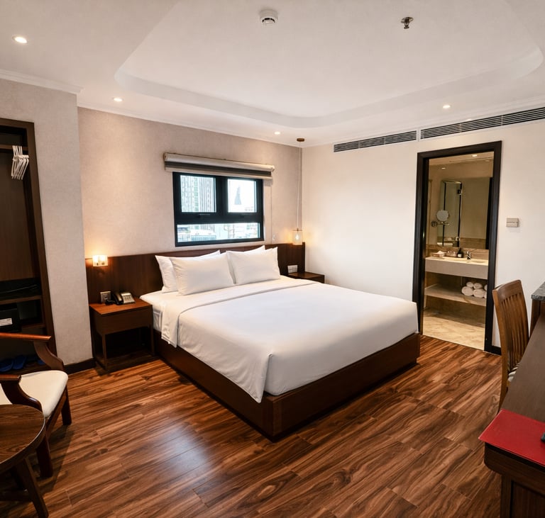 Modern hotel room with king bed, hardwood floors, wooden furniture, and ensuite bathroom.