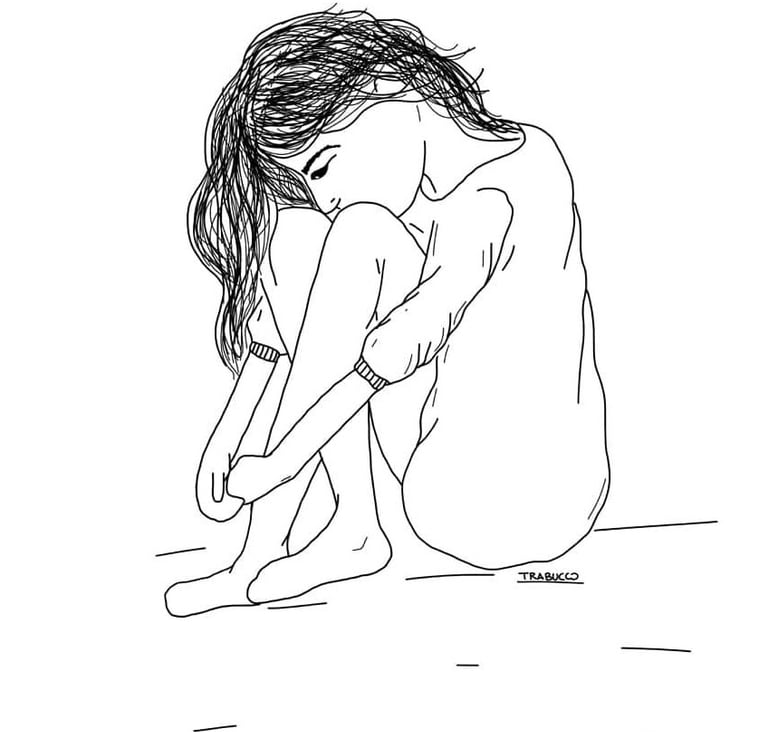 Una chica sentada con las piernas dobladas hacia ella, mirando al piso reflexionando