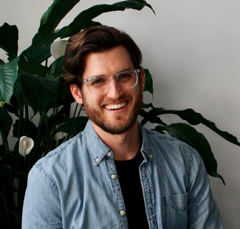 John smiling with plant behind him