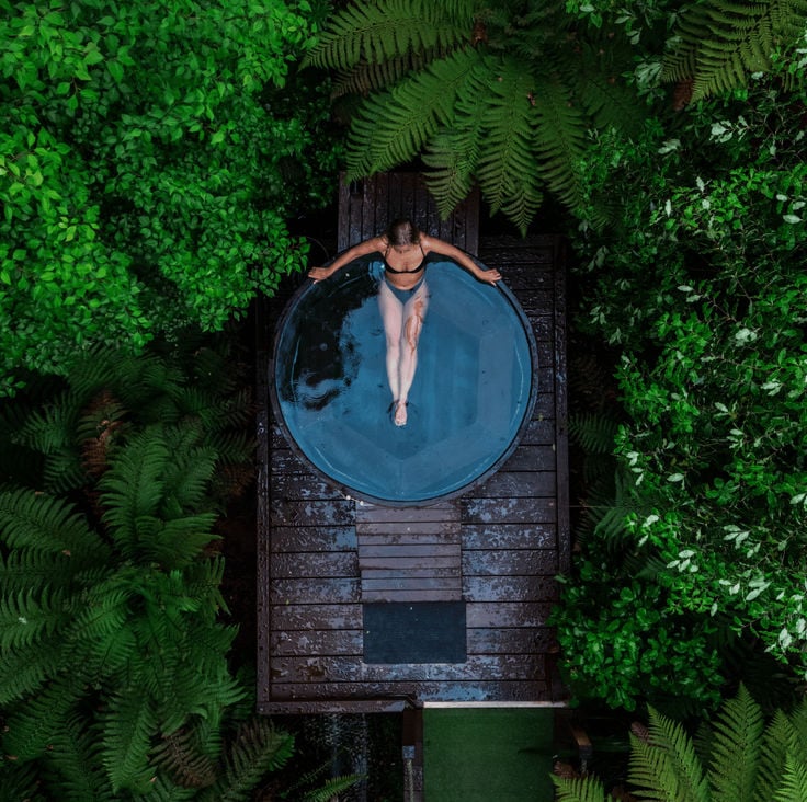 overhead view of a lady soaking in a jacuzzi in a forest