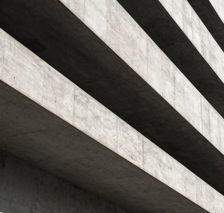 A close-up architectural shot of sharp concrete angles and deep shadows in a modern building in Rotterdam. The composition is minimalist, using charcoal and off-white tones to create a premium, geometric feel. Premium photography style.