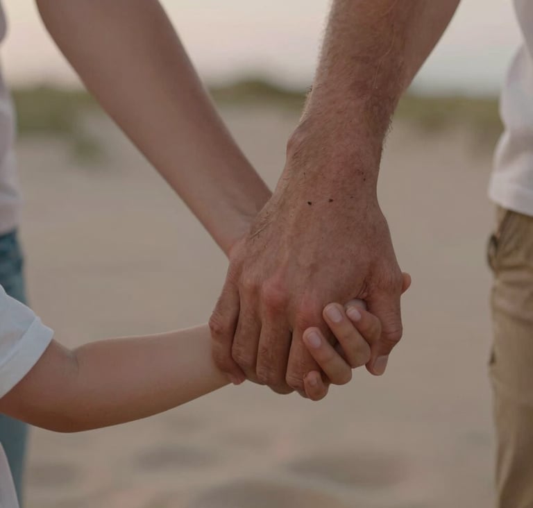 A close-up photograph of a family's hands joined together, showing a mix of adult and child hands. The scene is outdoors in North American / US (West Michigan) dunes at dusk. The palette includes Sand and Muted Rose colors with a soft, warm glow.