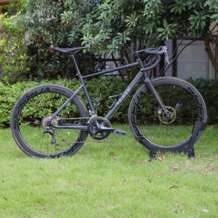 A matte black Triban road bike with deep section carbon wheels parked on a green lawn. RC500