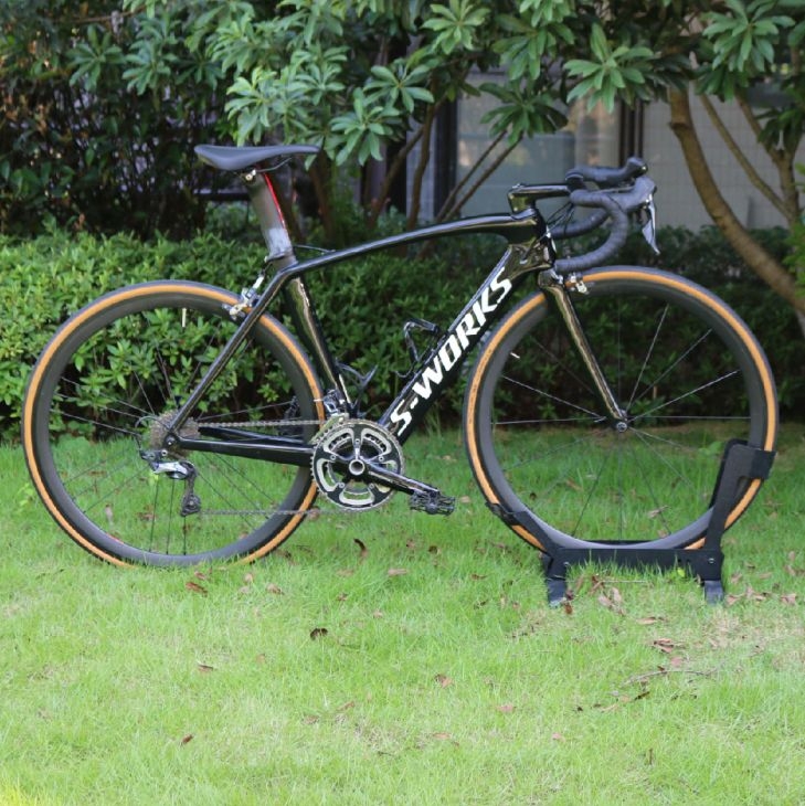 A black Specialized S-Works Venge carbon fiber road bike with tan wall tires parked on a green lawn.