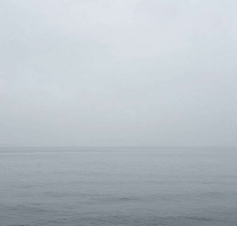 Contemporary photography showing a minimalist horizon where a calm gray sea meets a misty sky. The palette uses #D0D5DB and #F5F7FA to create a seamless, immersive atmosphere.