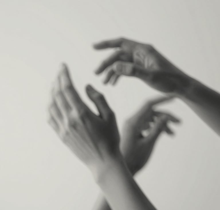 Artistic detail of hands in motion, captured with a slow shutter speed to suggest fluidity. Fine art style with a mix of #4C4A48 and #F5F2EF tones, emphasizing the elegance of human form.