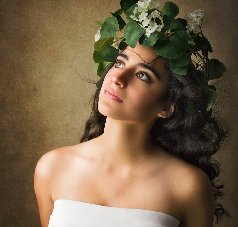 a gorgeous girl with long black curly hair looking up as the wind blows her hair away, she wears a vines crown with flowers