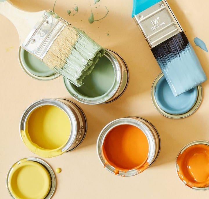 Ekologiczne farby w pastelowych kolorach. Otwarte puszki gotowe do malowania a na nich pędzle