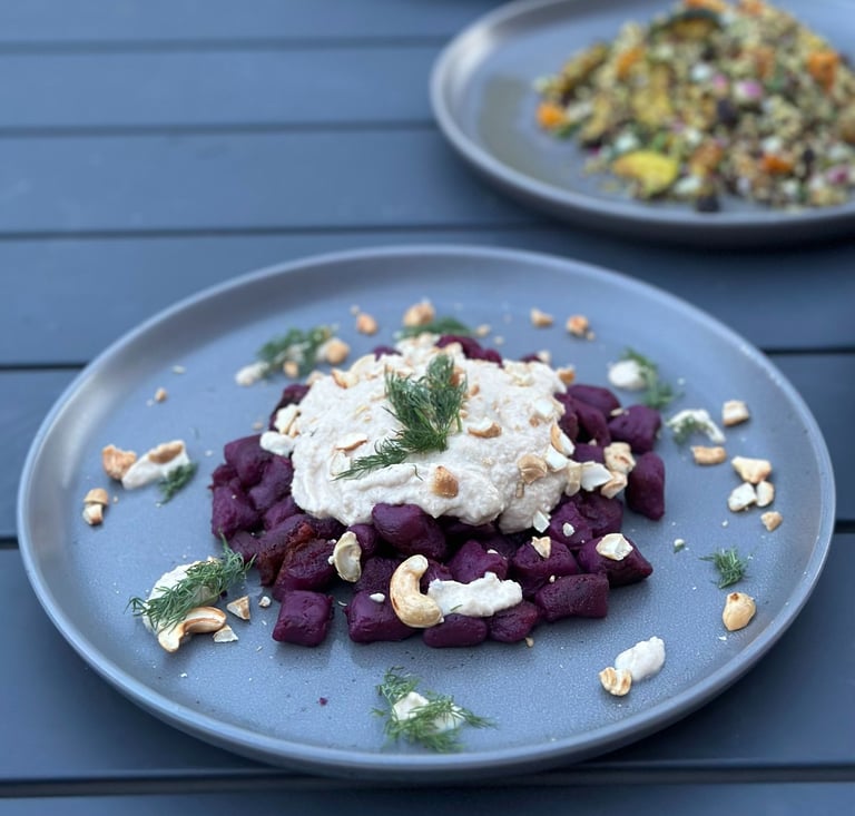a plate of beetroot gnocchi on a table with a plate of food